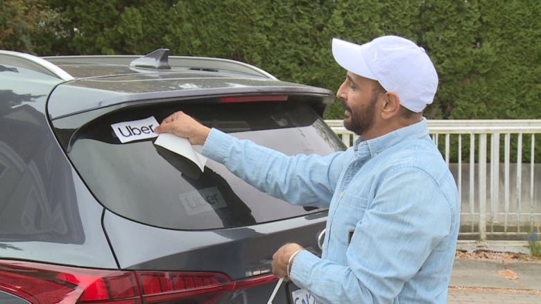 Hail driver placing Uber sticker on vehicle.